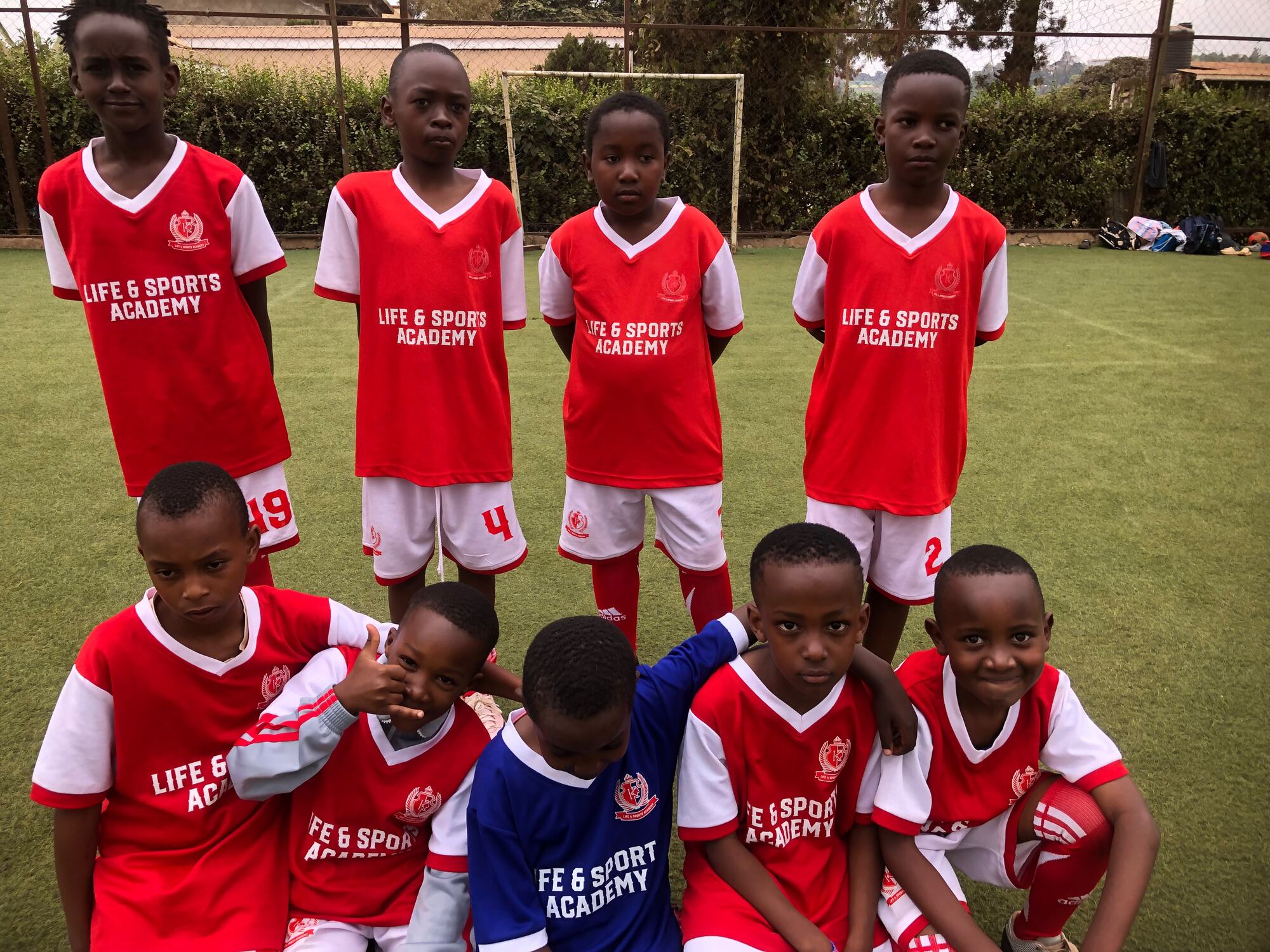 An LSA junior squad in the red home kit, posing on the pitch